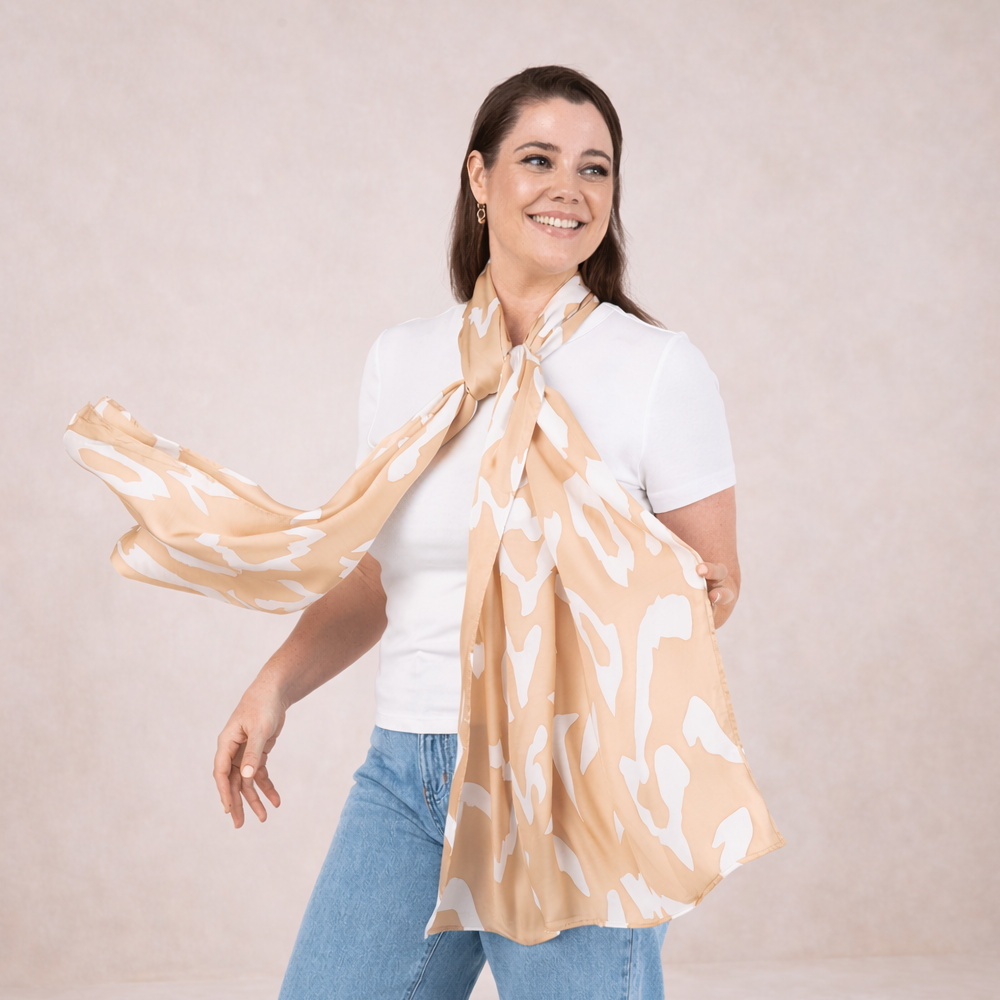 Woman wearing a beige scarf with white patterns on a plain background