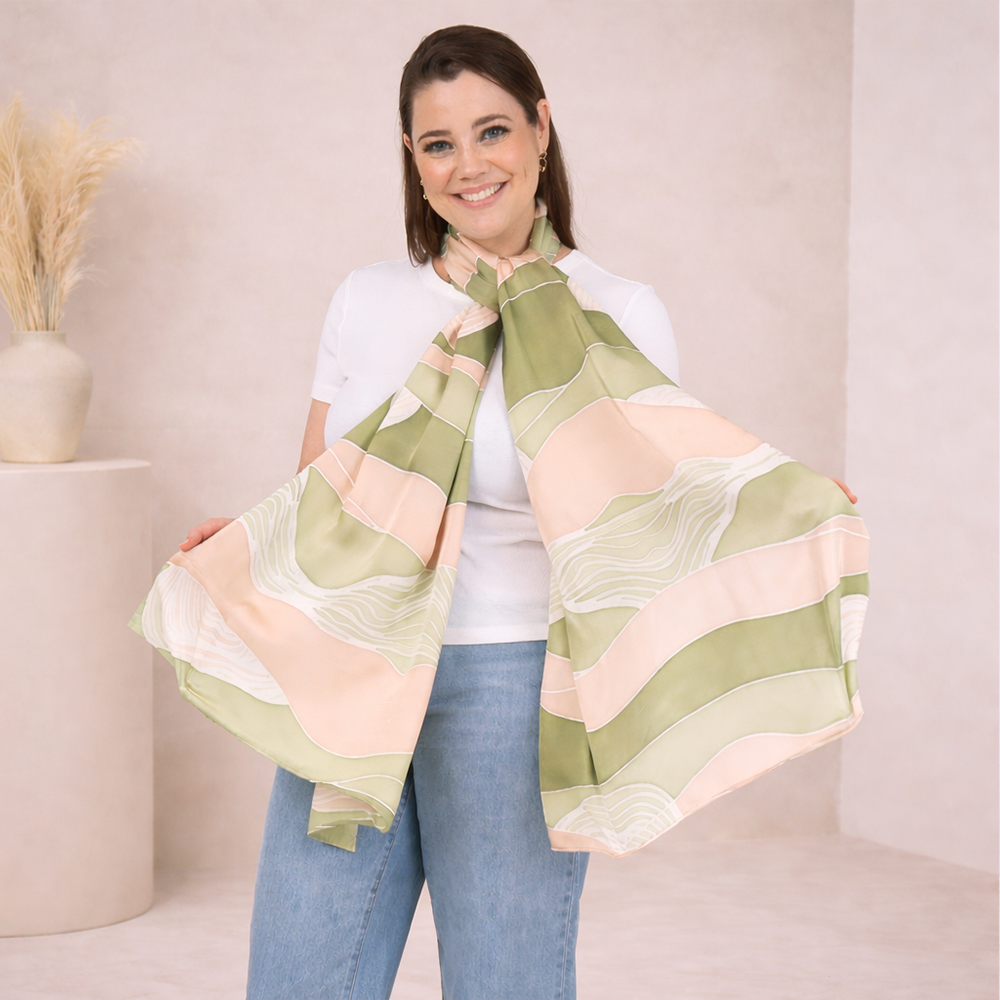 Woman wearing a large green and pink patterned scarf on a plain background