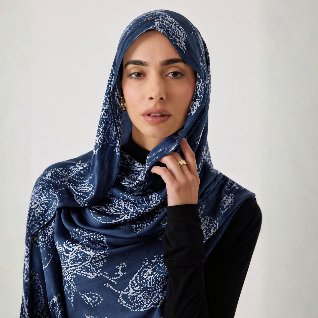 Woman wearing a blue patterned hijab against a plain background