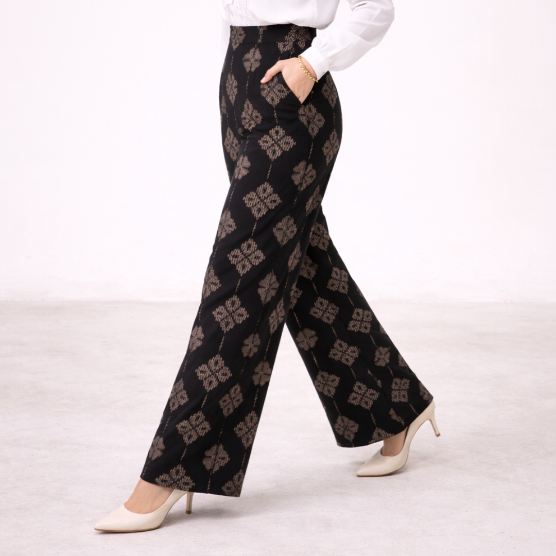 Person wearing black patterned pants on a white background