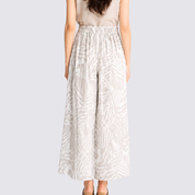 Woman wearing grey printed batik wide leg trousers facing the back showing the back details