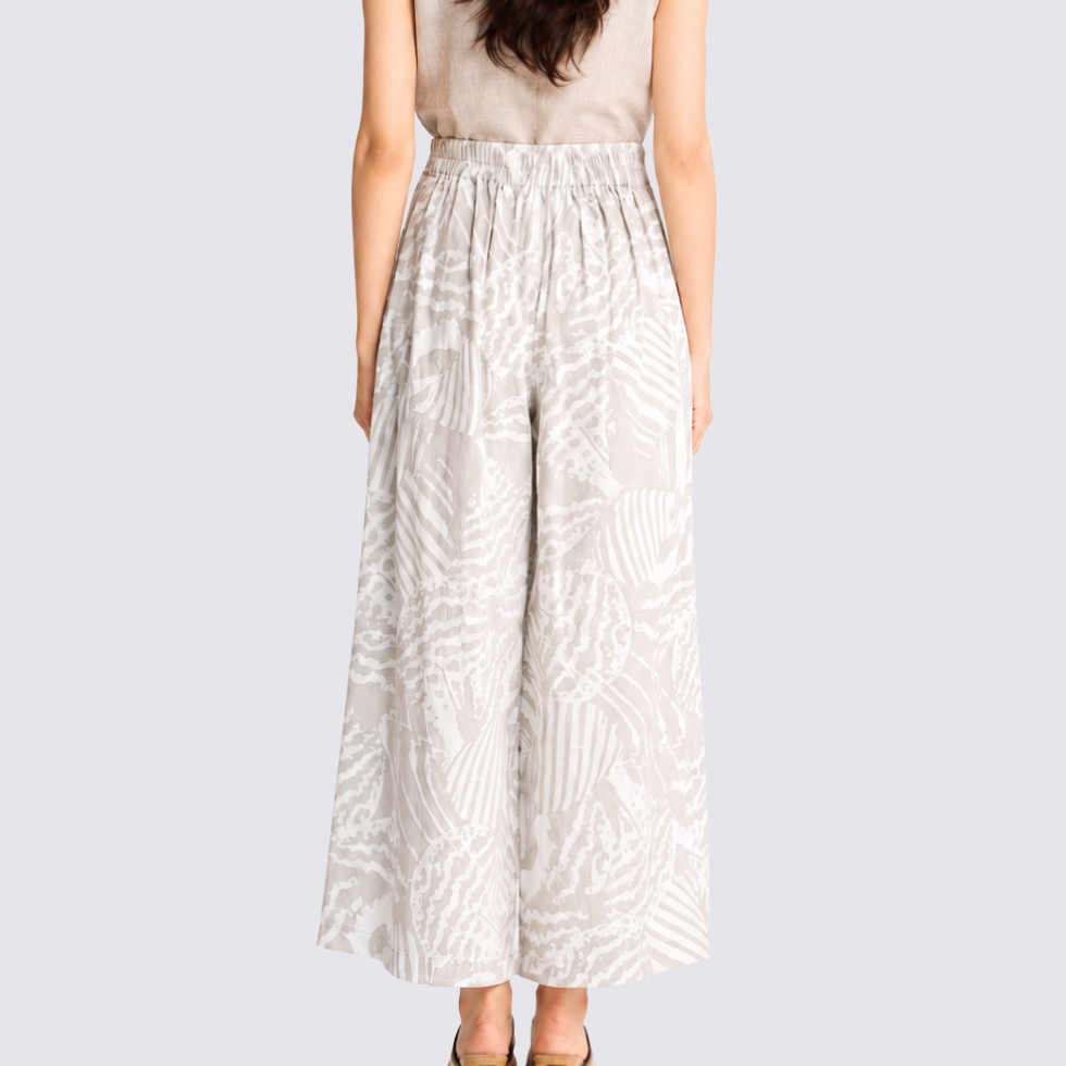 Woman wearing grey printed batik wide leg trousers facing the back showing the back details