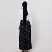 Person wearing a black patterned abaya and white blouse on a light gray background