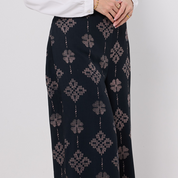 Black patterned pants worn by a person on a white background