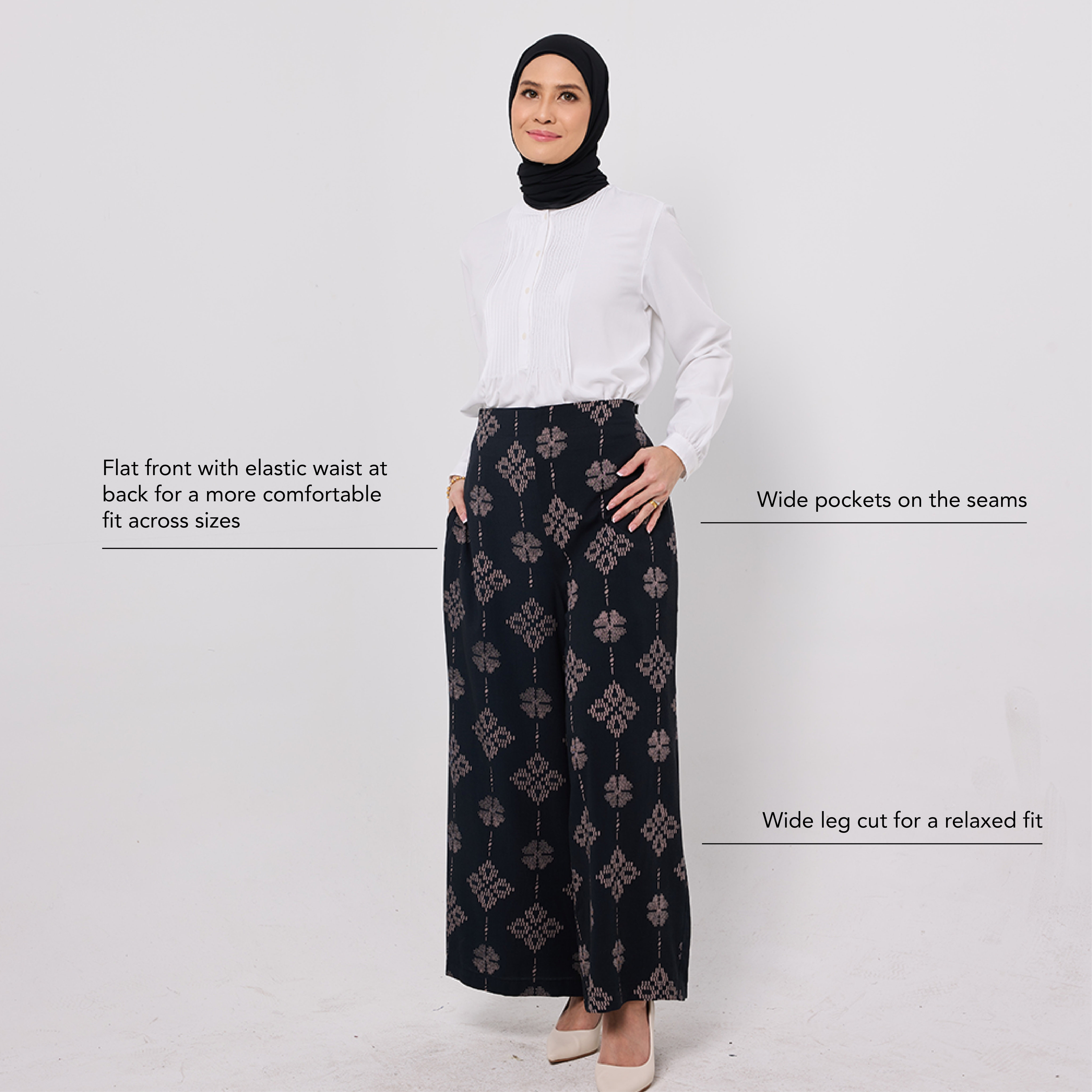 Woman wearing a white blouse and black patterned pants on a light gray background