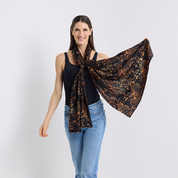 Woman wearing a black and orange patterned scarf on a white background