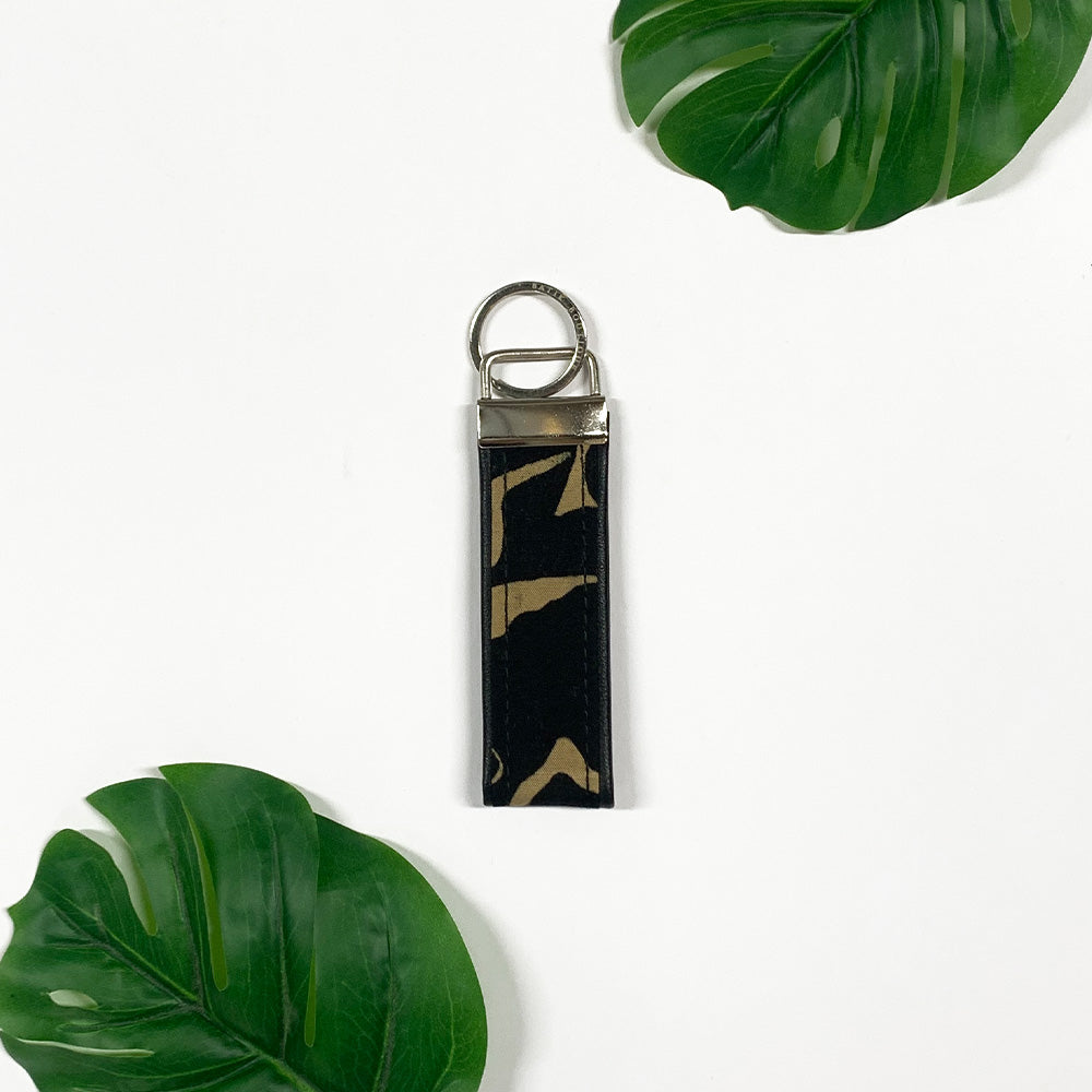 a lifestyle picture of black diwanie key fob made of batik remnants against a neutral background