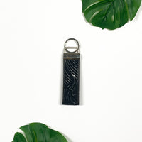 a picture of black driftwood key fob made of batik remnants against a neutral background