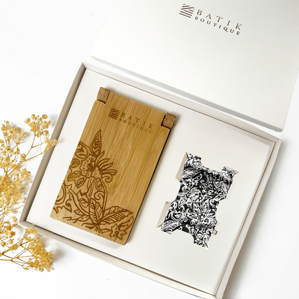 a whitebox set of congkak and batik pouch int he pattern balck floret against a white background