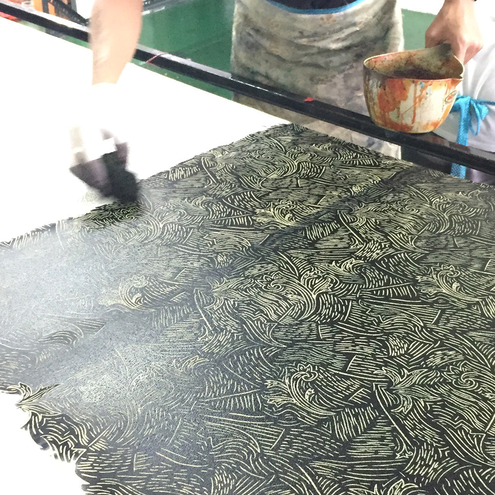 An artisan is painting batik in black driftwood pattern