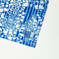 a close up shot of a batik scarf in the pattern blue bintik against a white background with the batik boutique logo embroidered at the corner of the scarf