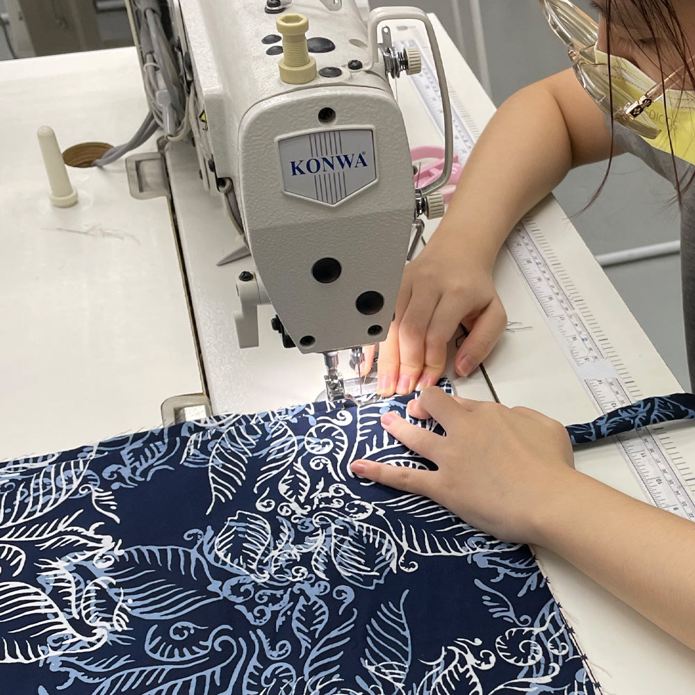 a seamstress in the process of sewing batik in the pattern blue nautical fern