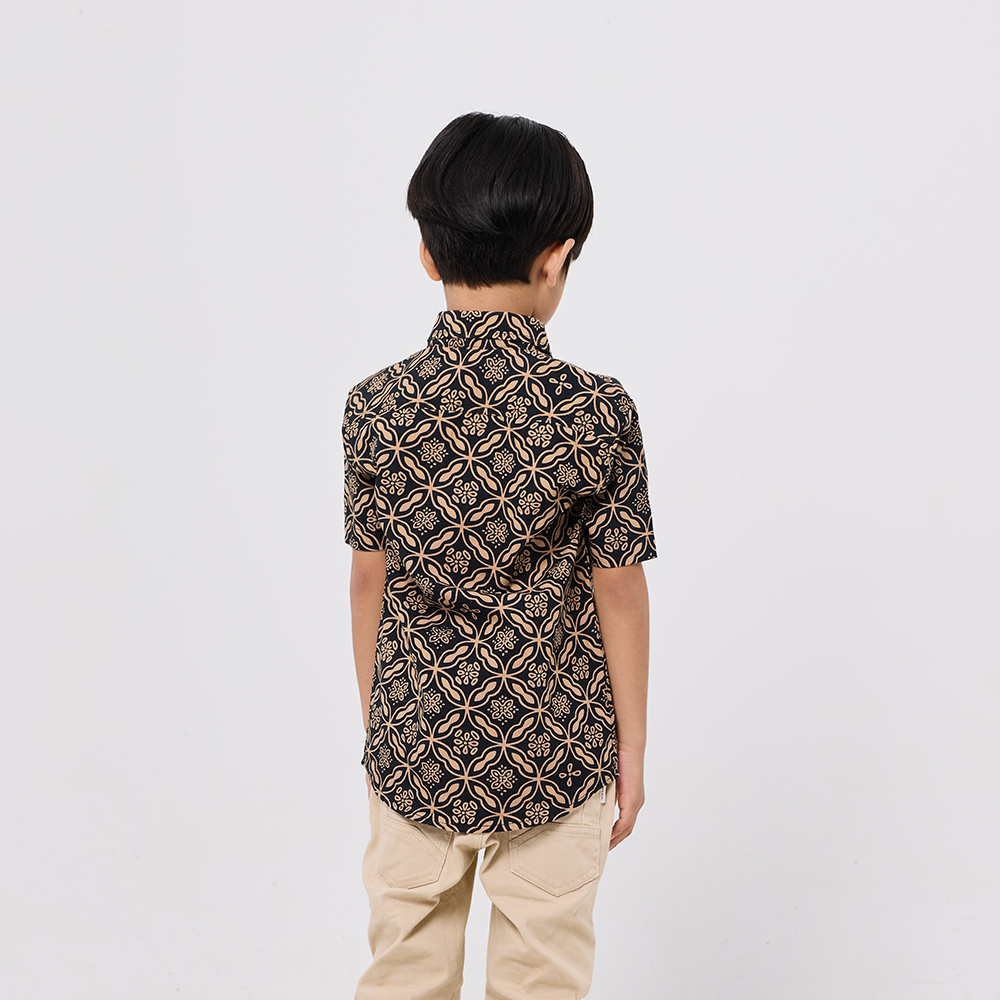 Child wearing a patterned shirt and beige pants on a white background