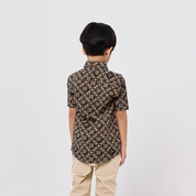 Child wearing a patterned shirt and beige pants on a white background