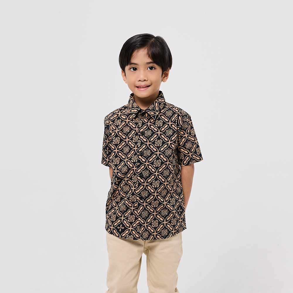 Child wearing a patterned shirt and beige pants on a white background
