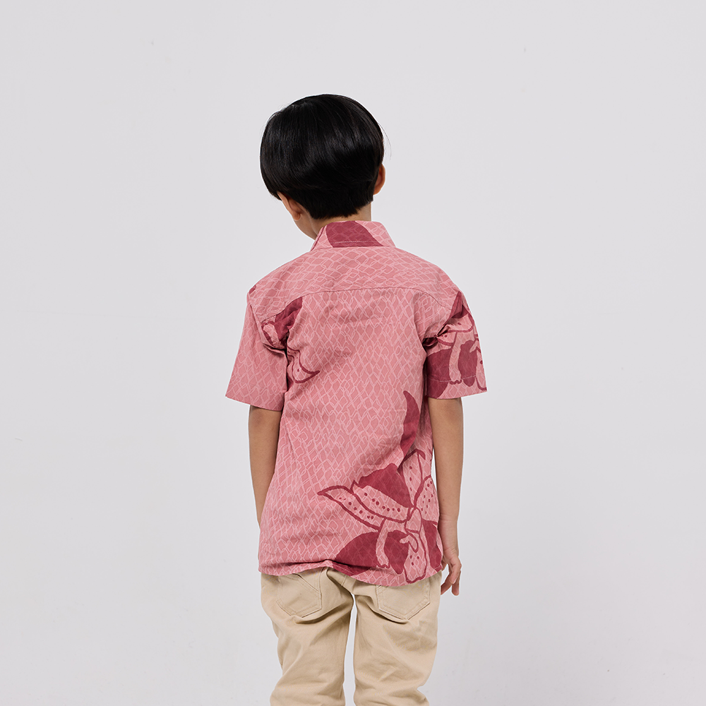 Person wearing a pink patterned shirt and beige pants on a white background