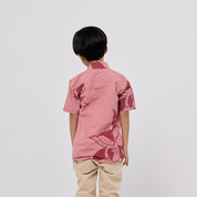 Person wearing a pink patterned shirt and beige pants on a white background
