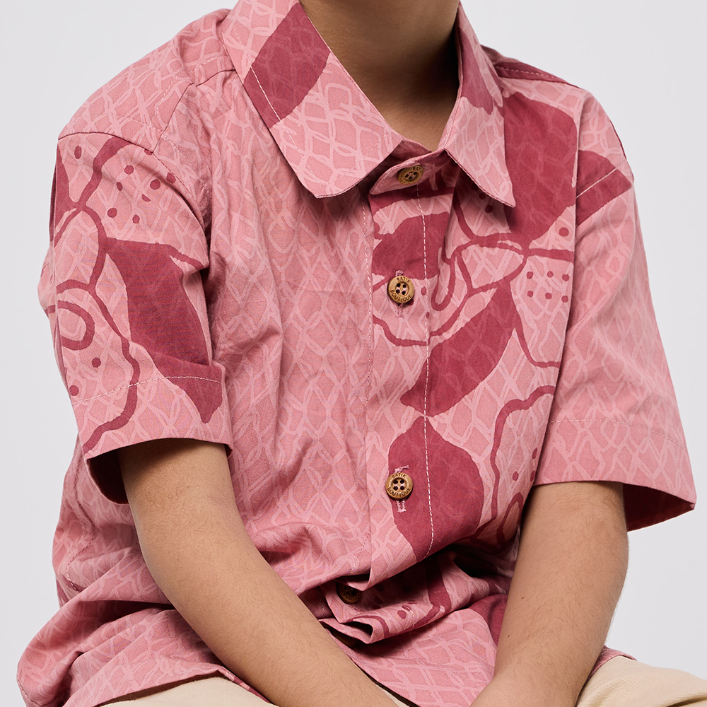 Person wearing a pink patterned shirt with a plain background