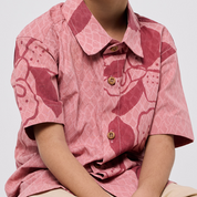 Person wearing a pink patterned shirt with a plain background