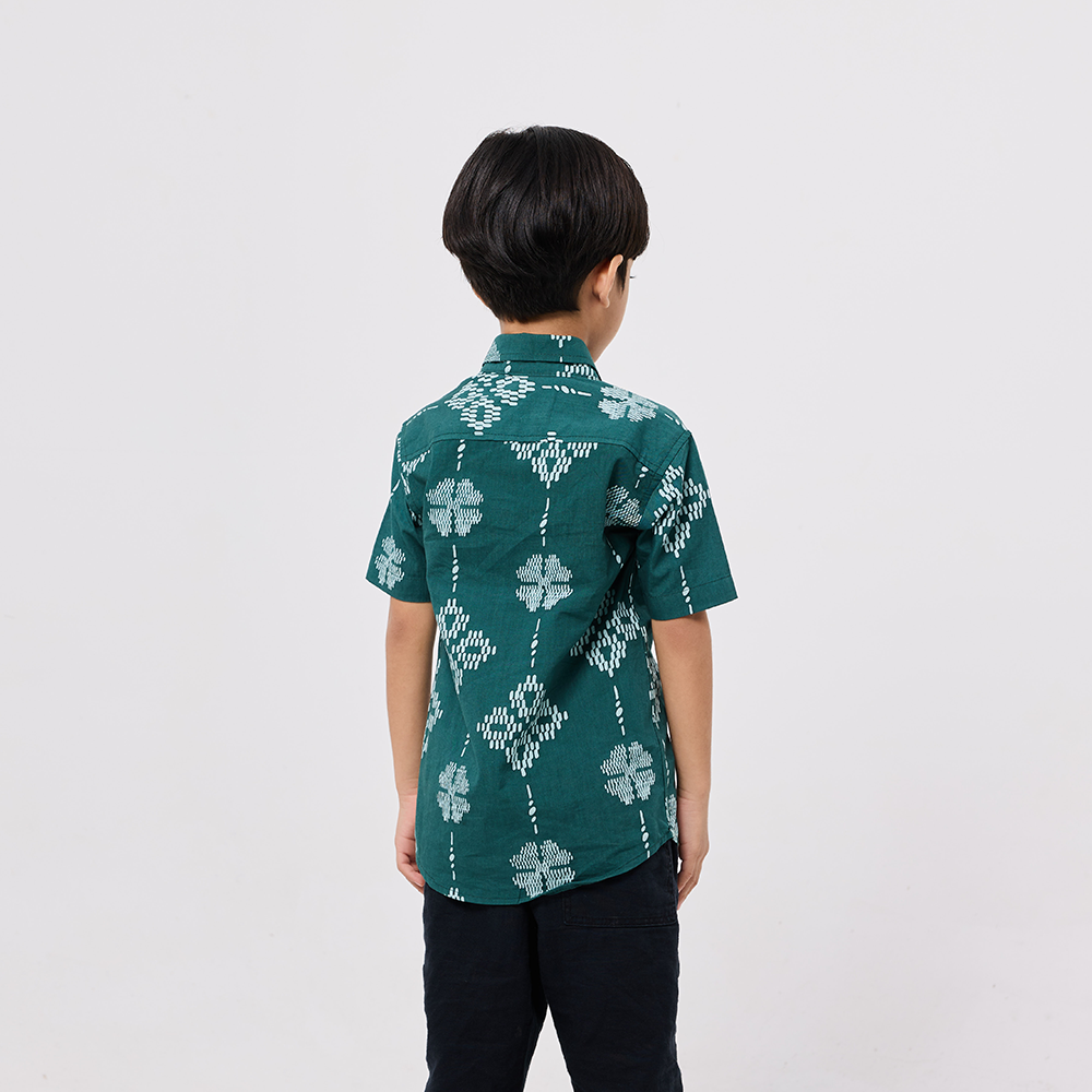 Child wearing a green patterned shirt on a white background