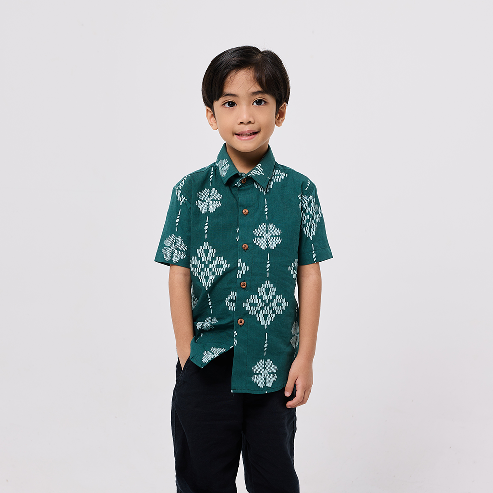 Child wearing a green patterned shirt on a white background