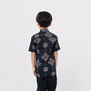 Child wearing a dark patterned shirt on a white background