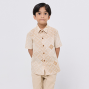 Child wearing a beige patterned shirt and pants on a white background