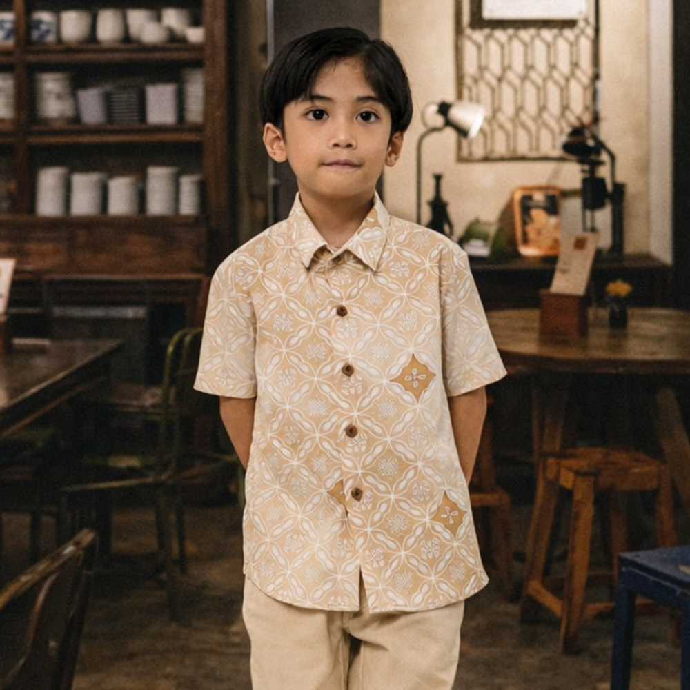 Young boy in a patterned shirt standing in a rustic interior setting