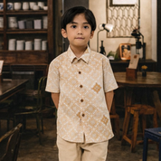 Young boy in a patterned shirt standing in a rustic interior setting