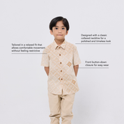 Child wearing a beige patterned shirt and pants on a white background