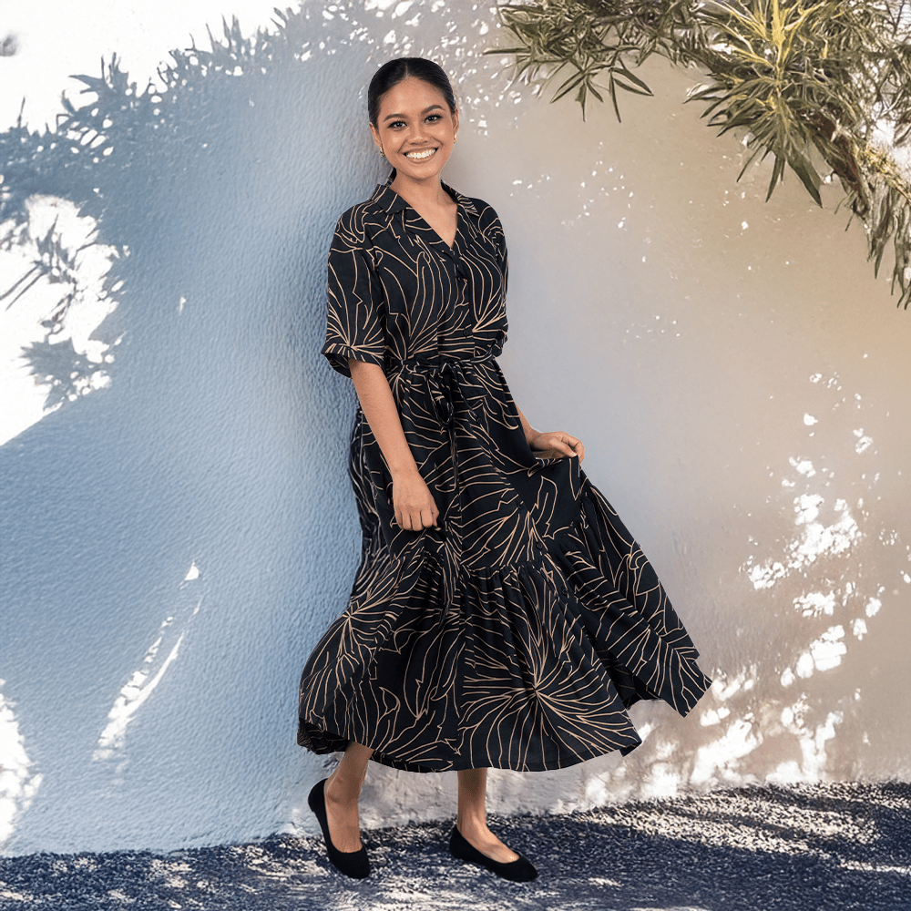 Woman wearing Batik Boutique’s Onyx Palma Button-Up Dress, inspired by Southeast Asian flora, styled outdoors in a flowy silhouette.