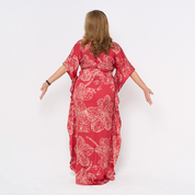 a woman facing away from the camera in the pattern crimson orchid in batik caftan dress