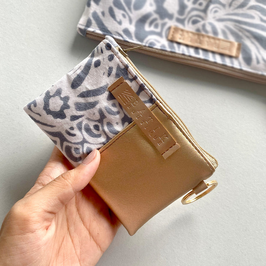 a lifestyle picture showcasing a card holder wallet made of batik in the pattern grey peony