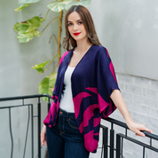 a female model posing in a batik cardigan kimono against a metal railing and greeneries in the pattern fuchsia rose