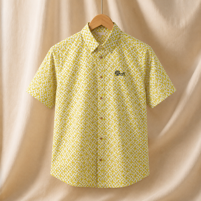 Yellow patterned shirt on a hanger against a beige curtain background