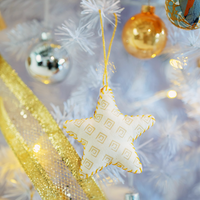 a lifestyle picture of a batik star ornament in the pattern tan nautical fern hanging on a tree with baubles on a white christmas tree