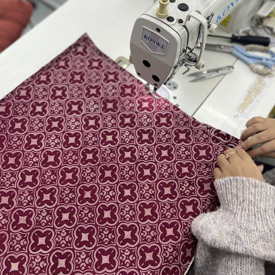 A seamstress is sewing batik fabric in crimson celestial 