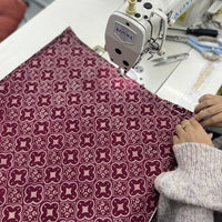 A seamstress is sewing a batik fabric in crimson celestial
