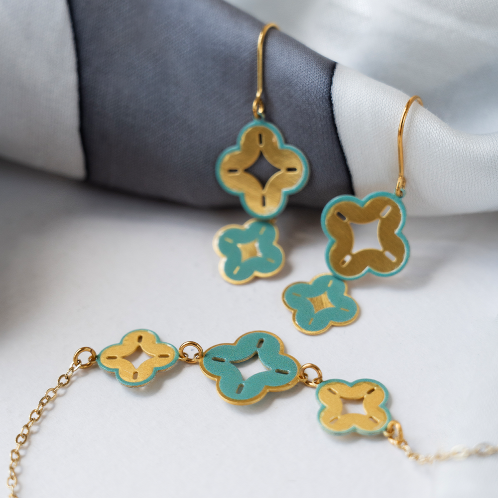 Celestial earrings paired with a matching bracelet in blue and gold, styled on a soft fabric background.