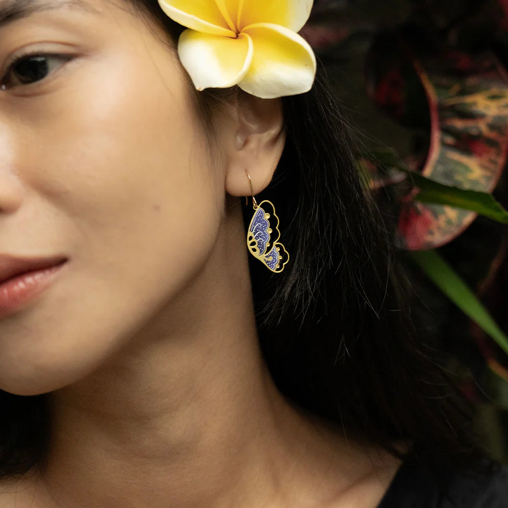 Close-up of a woman wearing a floral earring with a yellow flower in her hair.