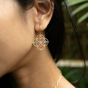 Close-up of a person wearing a decorative earring with a blurred natural background