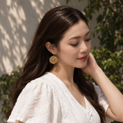 Girl wearing gold earring that resembles a hyrangea flower