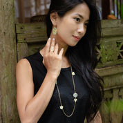 Woman wearing gold jewelry, including a necklace and earrings, against a wooden background.