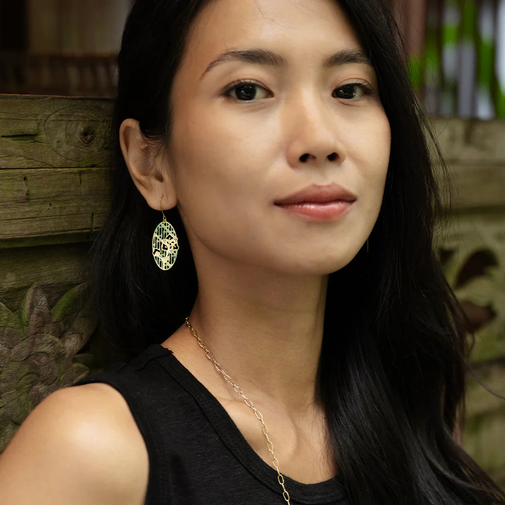Woman wearing a black top and gold necklace with a blurred natural background