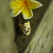 Gold ring with intricate design on a wooden surface with a yellow flower in the background