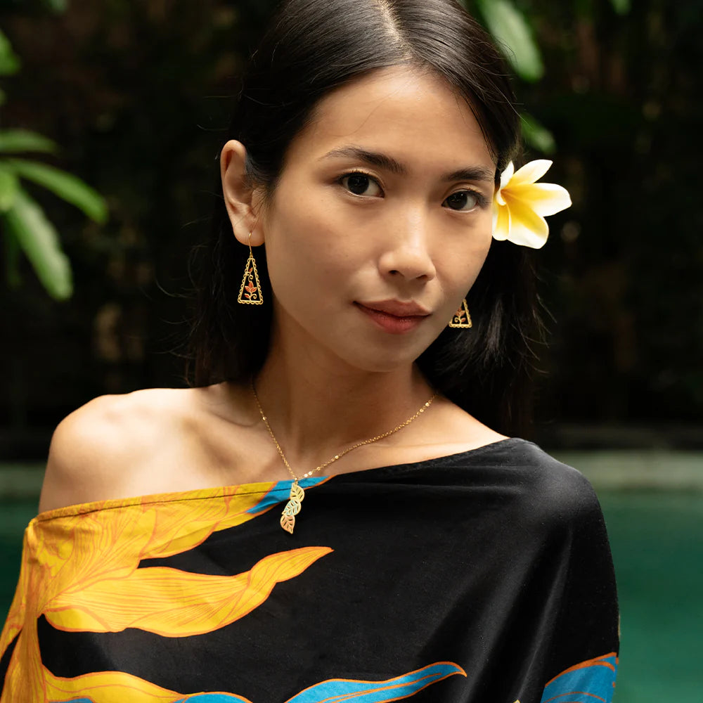Woman wearing a black and yellow traditional outfit with a flower in her hair, standing outdoors.