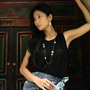 Woman in a black sleeveless top with a patterned skirt, standing indoors.