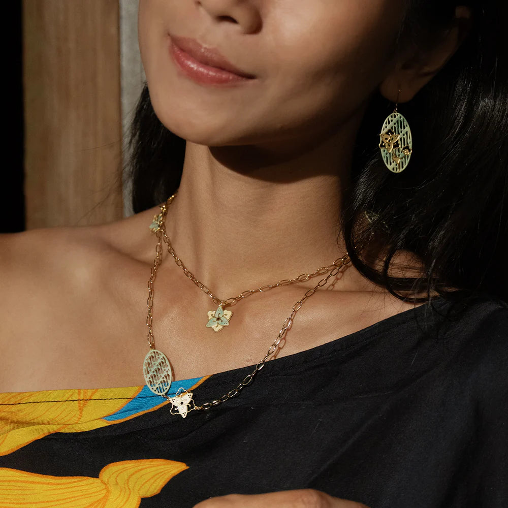 Woman wearing a gold necklace and earrings with a blurred background