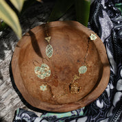 Gold necklace with green accents on a wooden surface