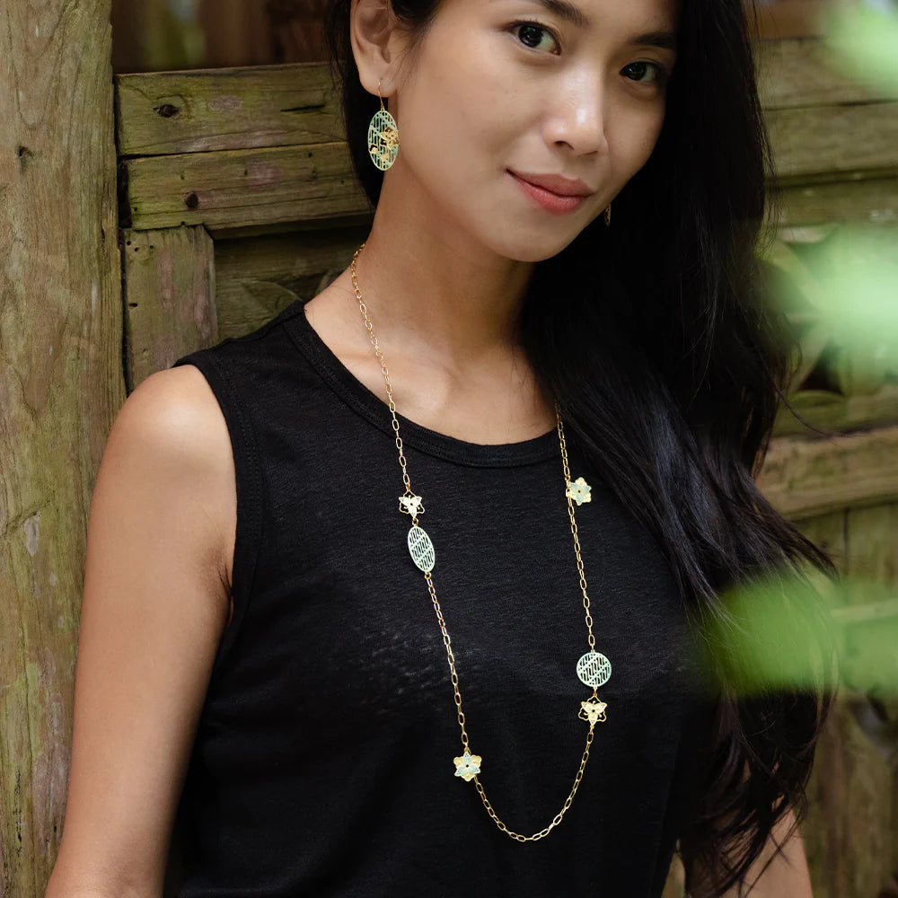 Woman wearing a long necklace with a wooden background